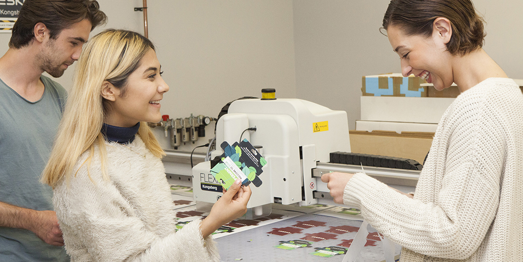 Three students working at a packaging cutting table
